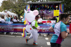 01.10.23 - Principality Building Society Cardiff Half Marathon 2023 - Roath Park and Lake - Runner dressed as unicorn goes past Rainbow Roundabout